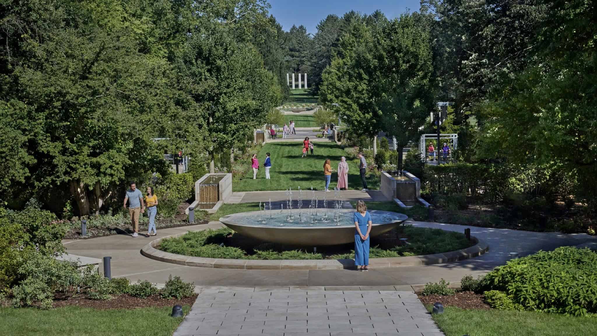 Image of a park with a fountain, grass and trees framing the sides