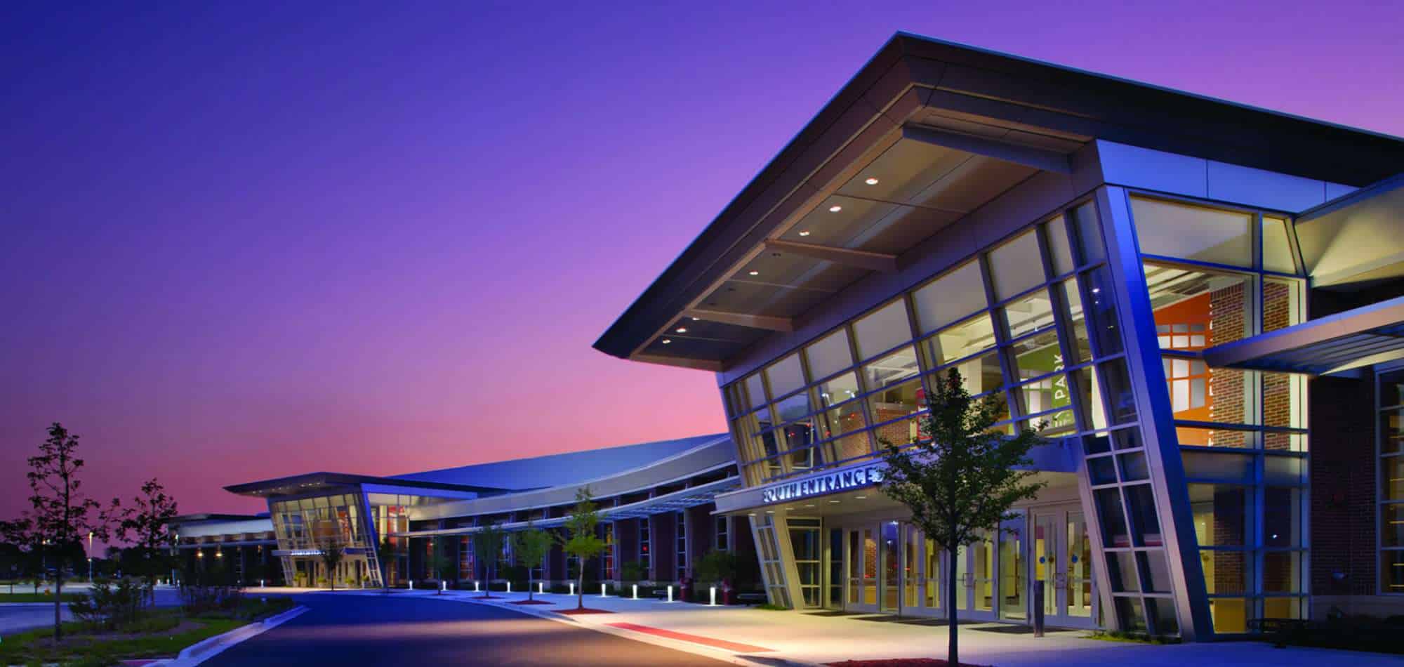 Image of a modern looking building during dusk with a pink and purple sky