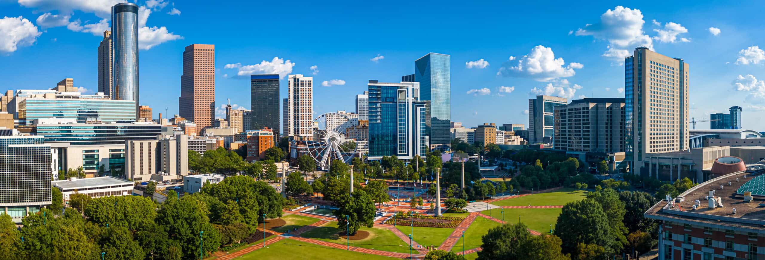 Daytime aerial view of downtown Atlanta skyline with parks, buildings, and clear skies